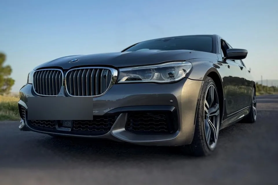 Серый BMW 750 M-пакет 2015 на загородной дороге на закате
